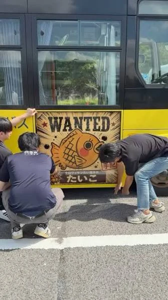 三豊のバスにたいこちゃんのWANTED広告を貼っている様子